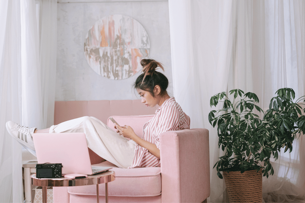 ピンクの部屋でスマホを見る女性