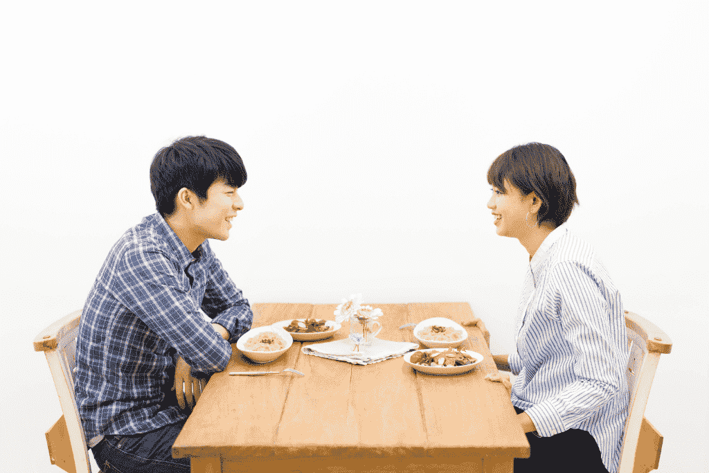 ダイニングテーブルで向かい合って食事をする男女
